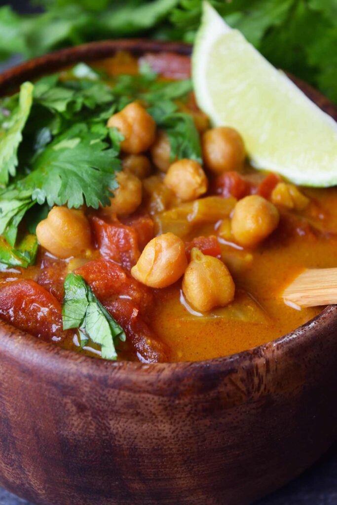 A closeup of a wood bowl filled with Chickpea Curry.