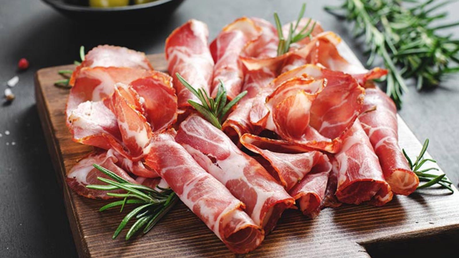 A cutting board full of sliced and folded, cured meats.