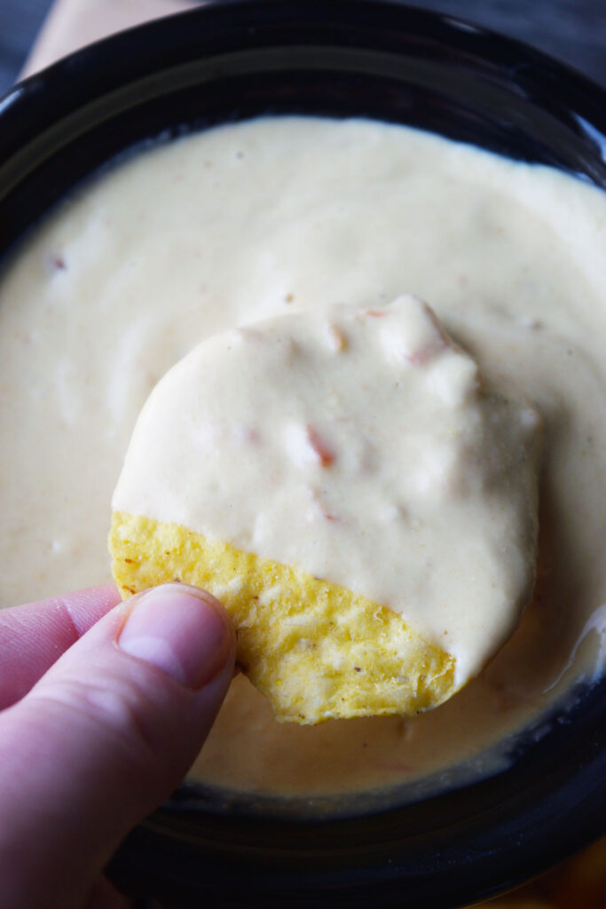 An overhead view of a chip covered in vegan cheese sauce.