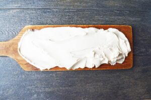 Cream cheese spread over a charcuterie board.