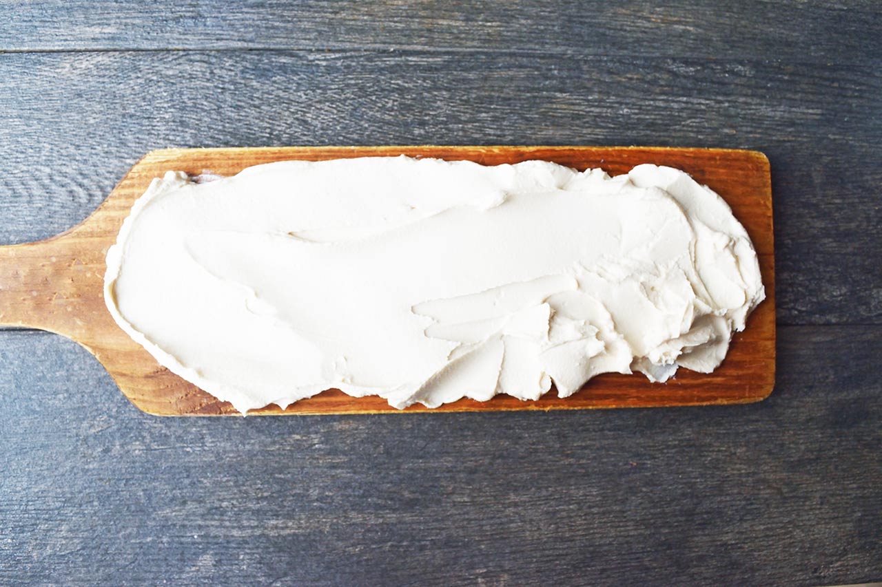 Cream cheese spread over a charcuterie board.