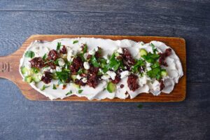 Fresh parsley sprinkled over the top of a Mediterranean Cream Cheese Dip board.
