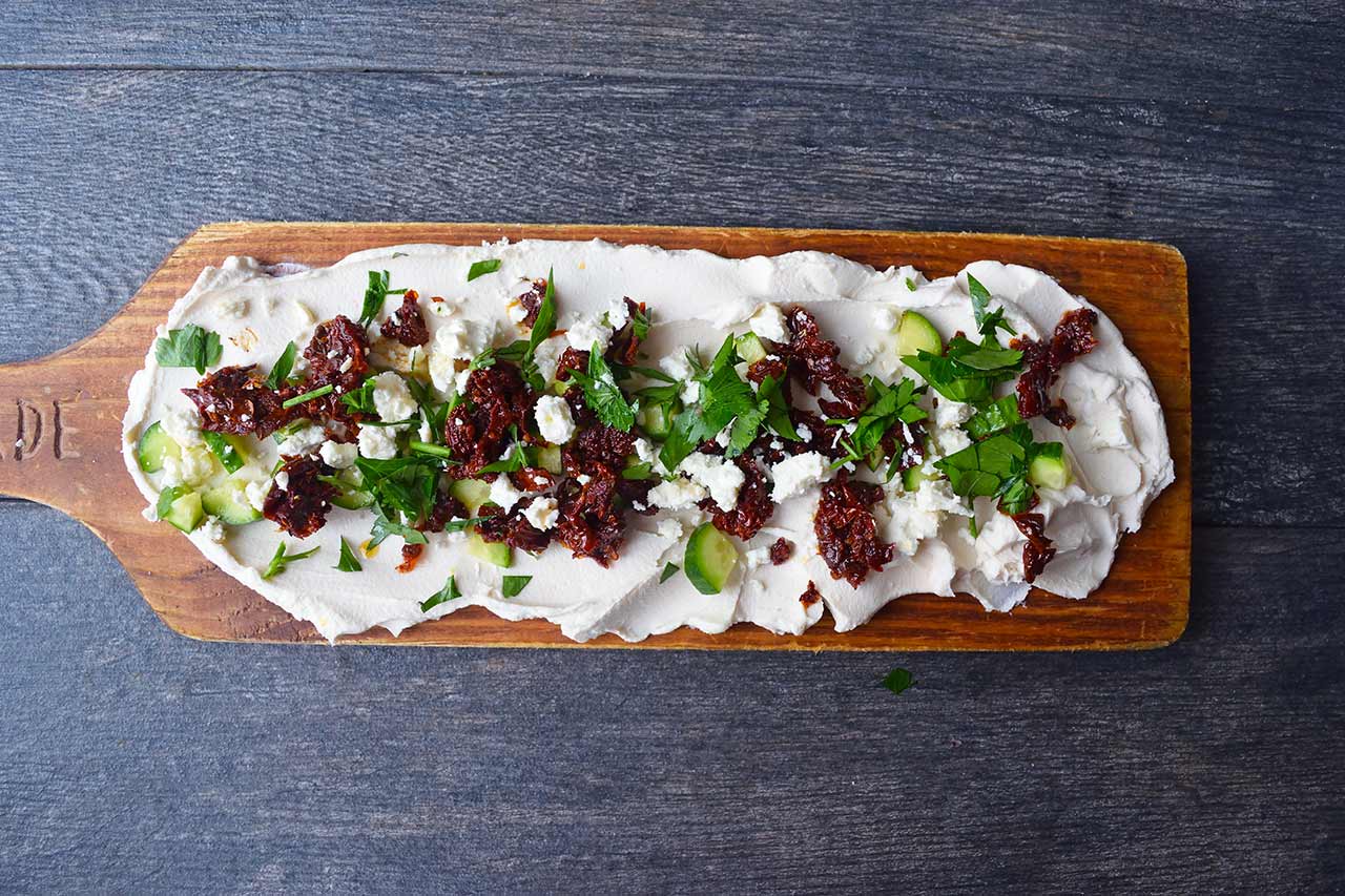 Fresh parsley sprinkled over the top of a Mediterranean Cream Cheese Dip board.