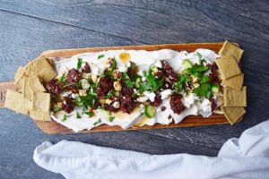 Crackers spread over the ends of a charcuterie board with Mediterranean Cream Cheese Dip.