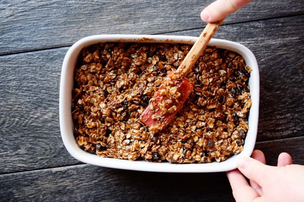 Pressing the granola bar batter into the casserole dish.