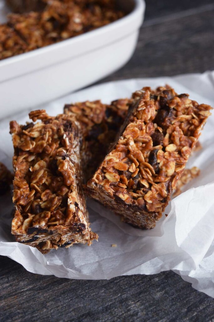 A closeup of three Homemade Granola Bars laying on parchment paper.