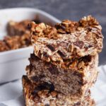 A stack of three No Bake Granola Bars sitting on parchment paper.