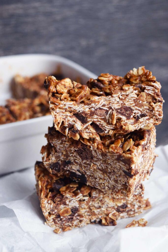 A stack of three Homemade Granola Bars sitting on parchment paper.