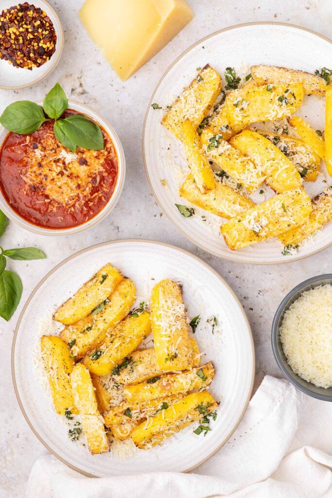 An overhead view of two plates filled with polenta fries.