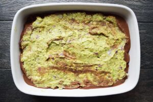 A layer of guacamole spread over a Taco Salad Casserole.