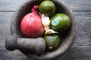 Guacamole ingredients in a mortar with a pestle.