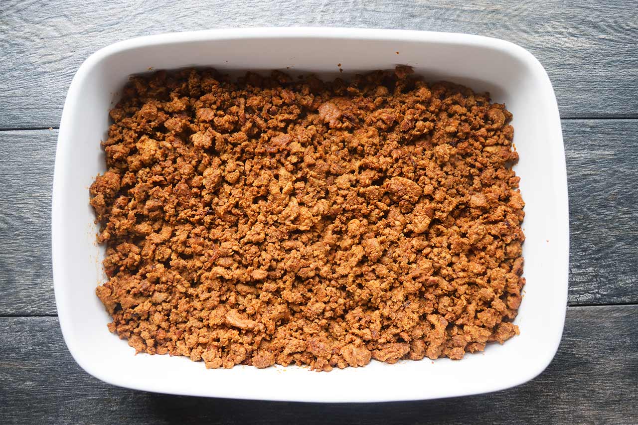 The first layer of the Taco Salad Casserole, ground turkey, in a white casserole dish.