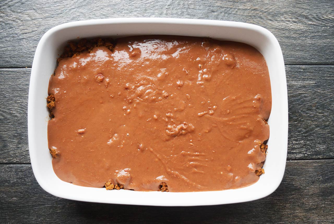 A layer of refried beans spread over the Taco Salad Casserole.