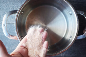 Adding salt to a pot of water.