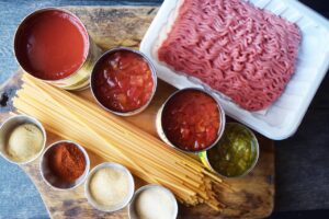 Ingredients for this Taco Spaghetti Recipe collected on a wood cutting board.