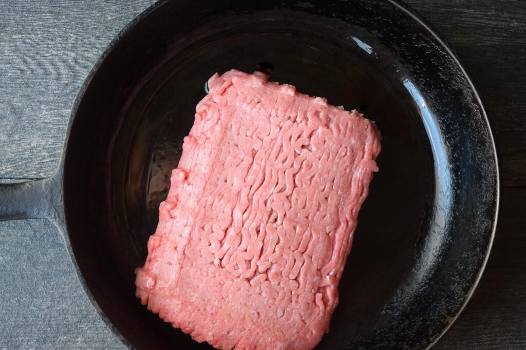 A pound of ground turkey in a skillet with oil.