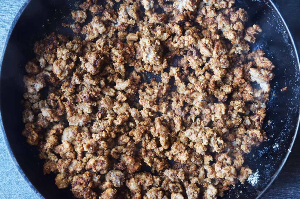 A skillet full of ground, seasoned turkey meat.