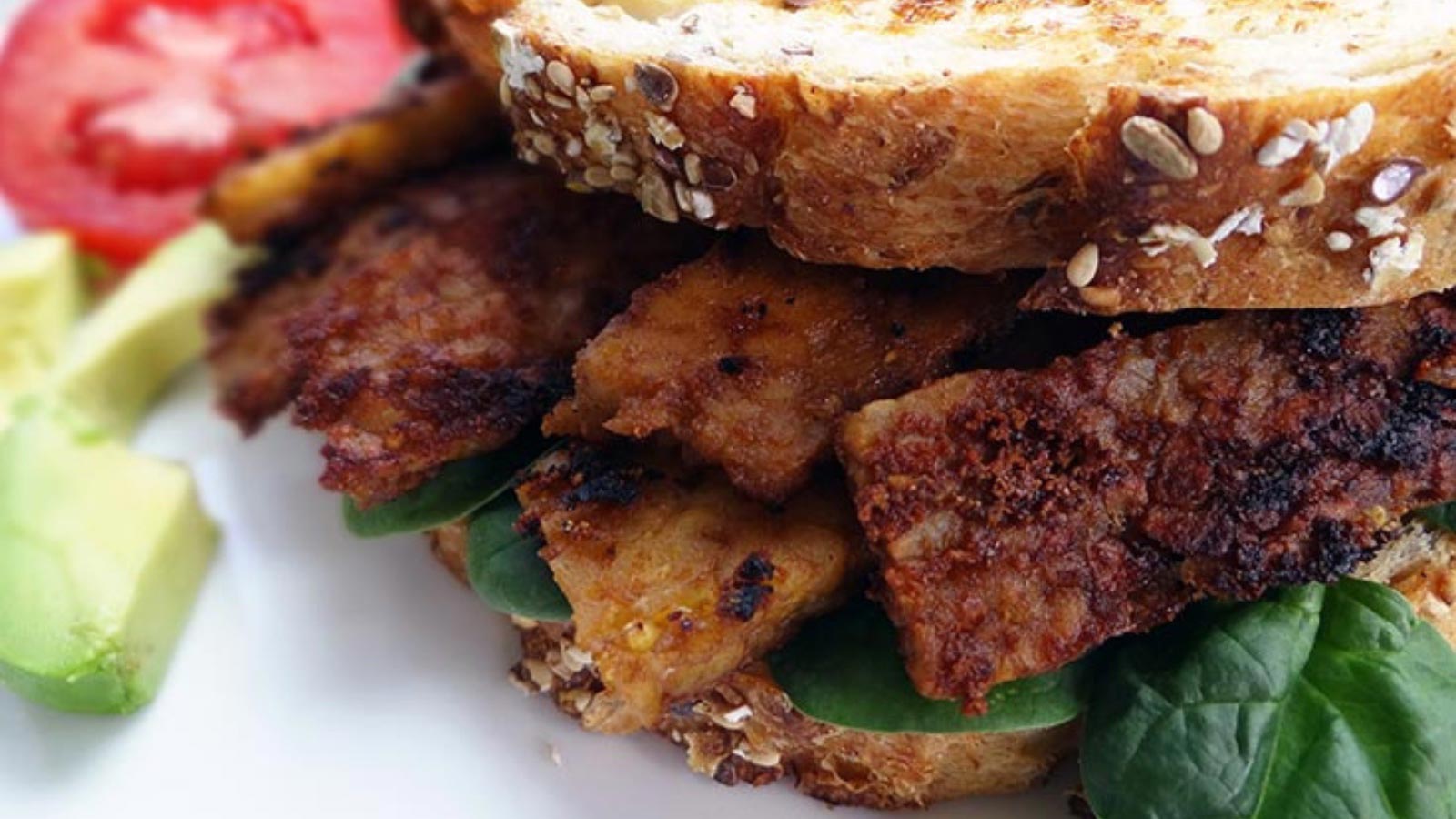 A sandwich made with tempeh bacon on a white surface.