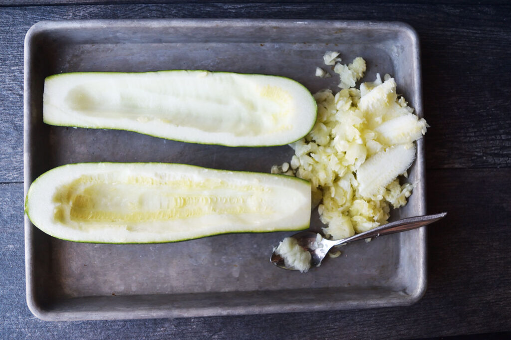 Seeds scooped out of two zucchini halves.