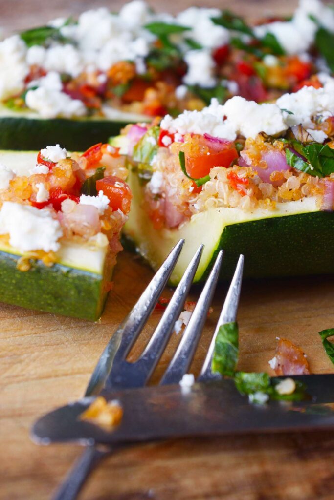 A closeup of a cut zucchini boat with a knife and fork.