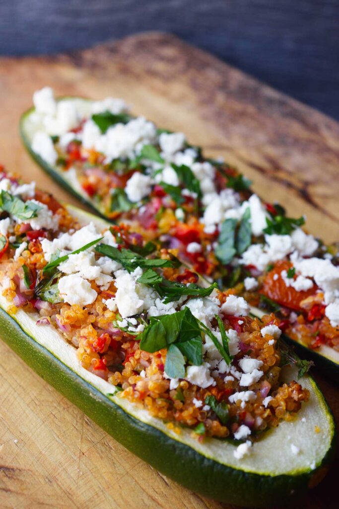 Two zucchini boats lined up on a wood cutting board.