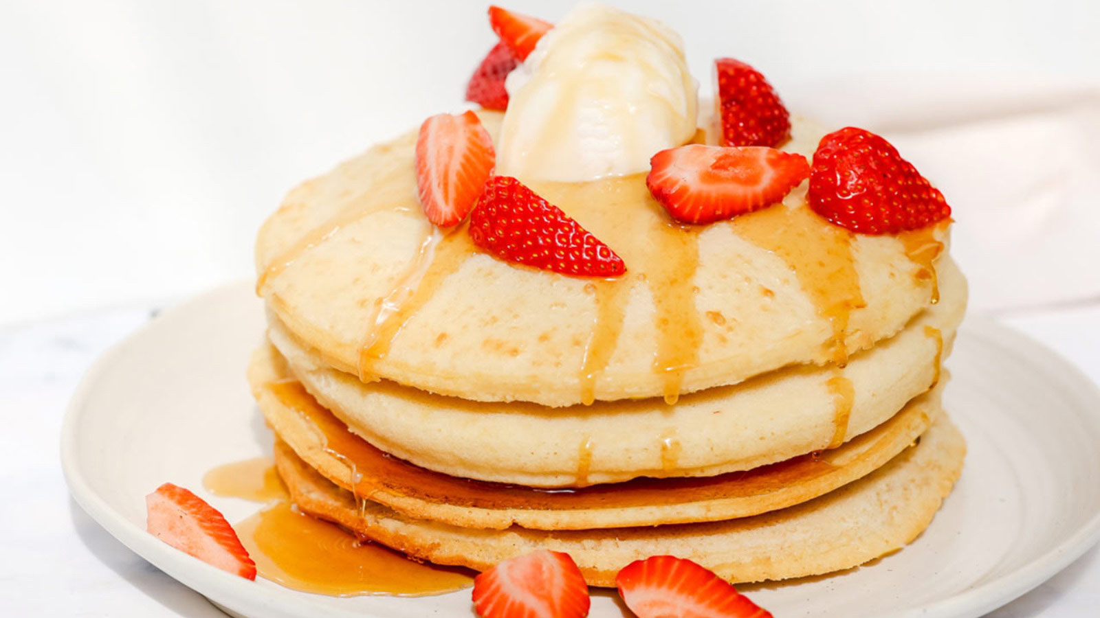 Air fryer pancakes topped with strawberries and syrup.