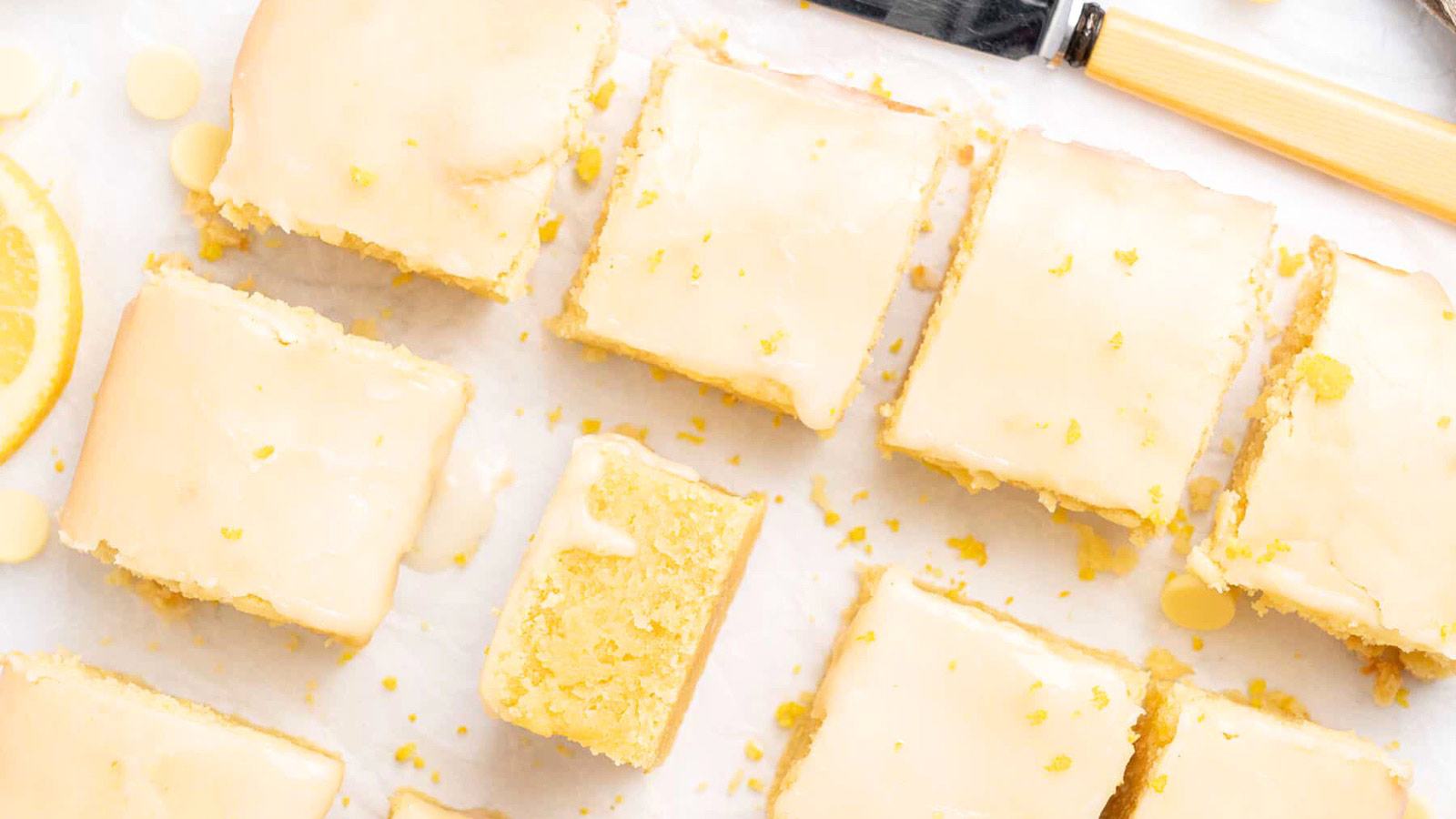 An overhead view of lemon brownies cut on white parchment paper.