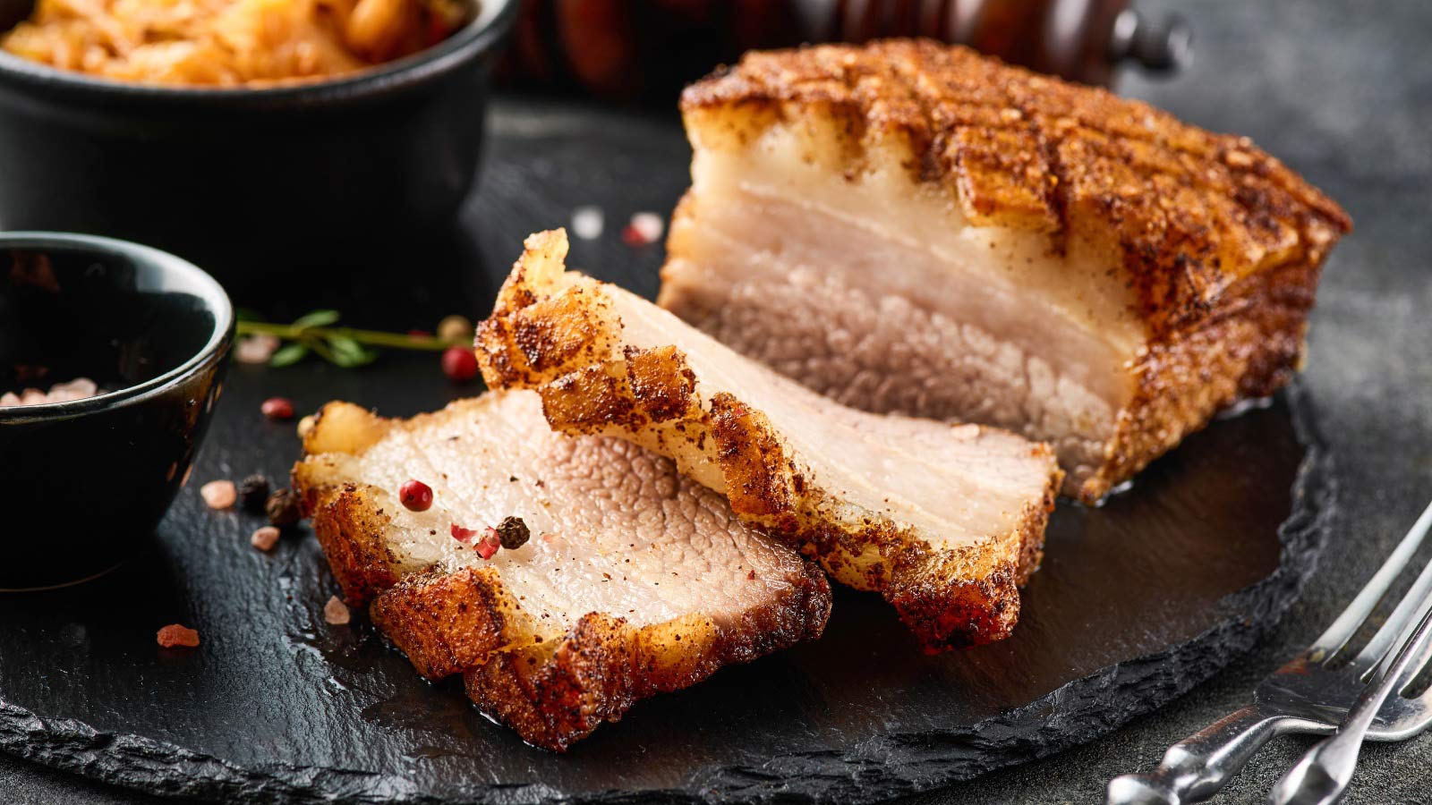 Sliced pork on a black, slate platter.