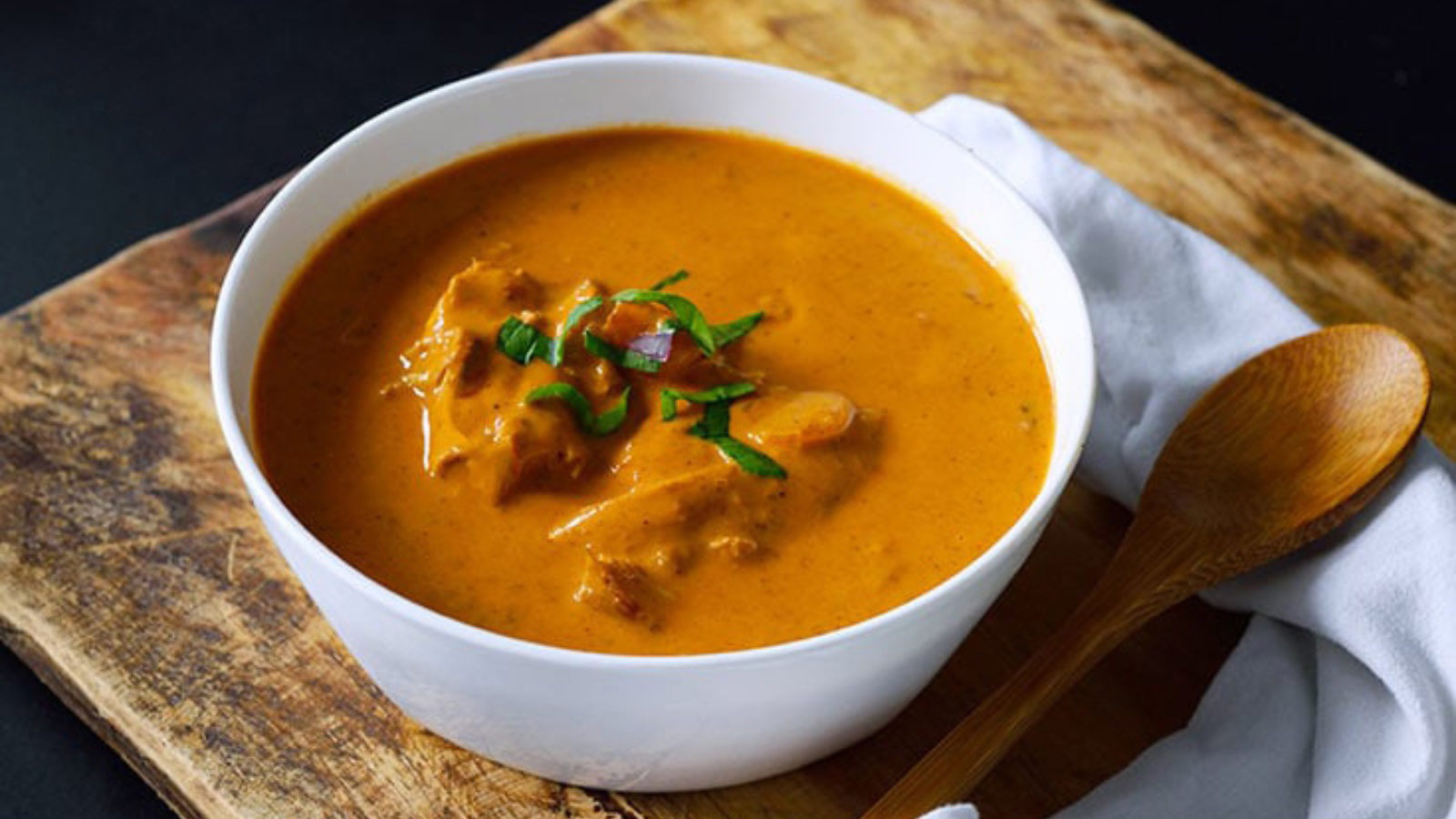 A bowl of Butter Chicken on a cutting board.