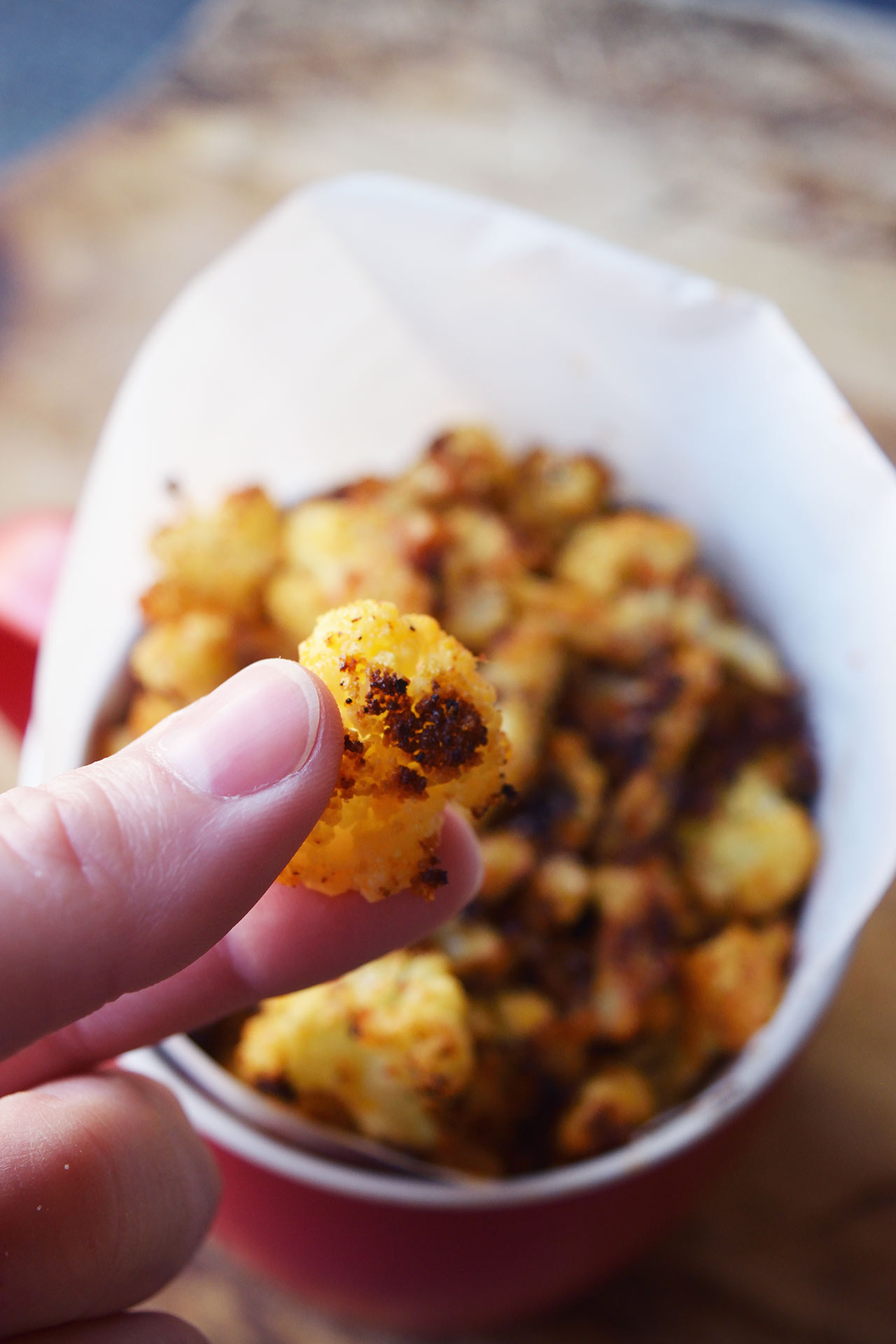 A hand holds up a single Cauliflower Popcorn.