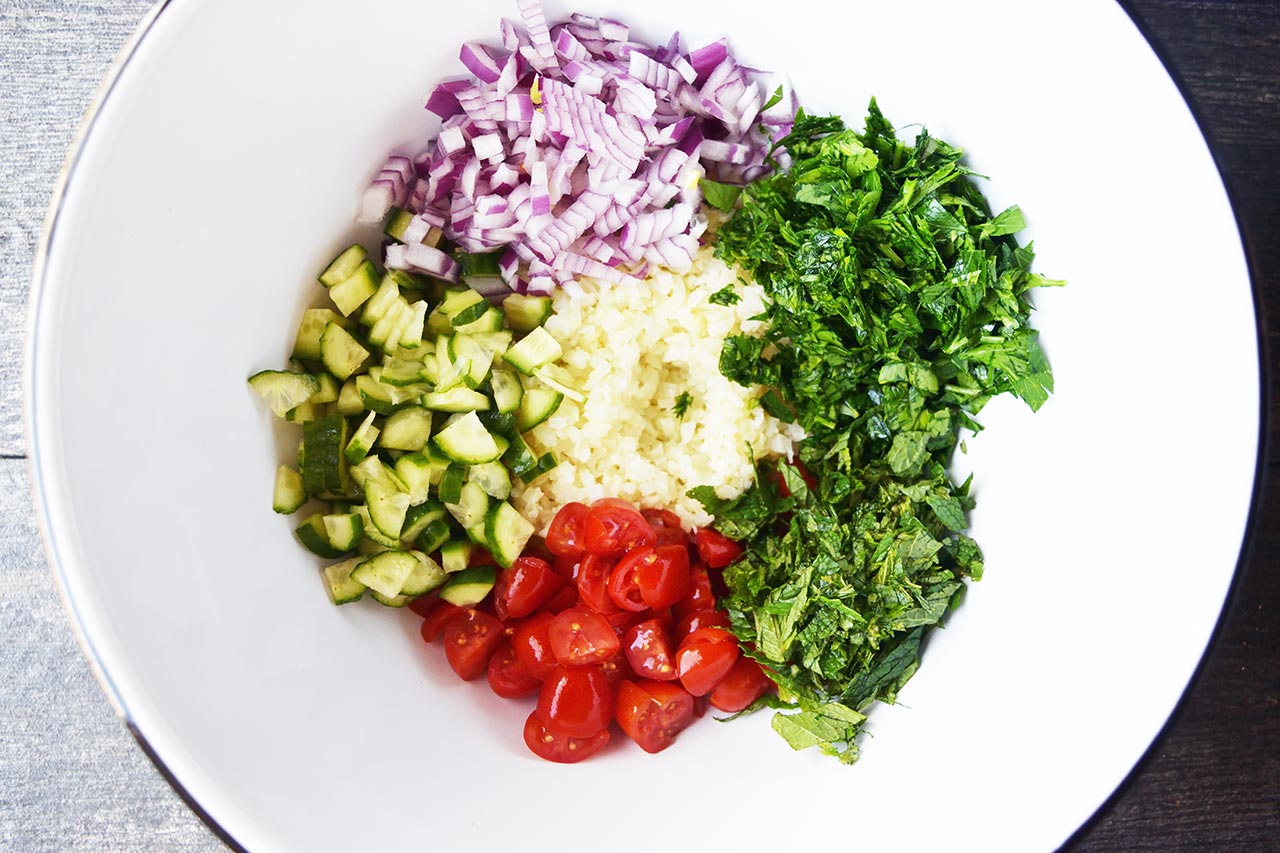 Cauliflower Tabouleh Recipe ingredients sitting unmixed in a mixing bowl.