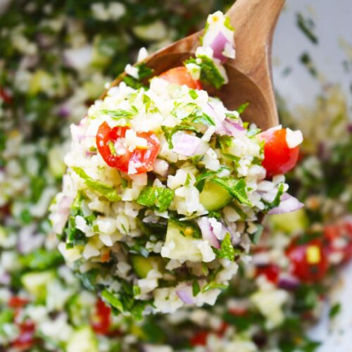 An overhead view of a wooden spoon full of Cauliflower Tabouleh.