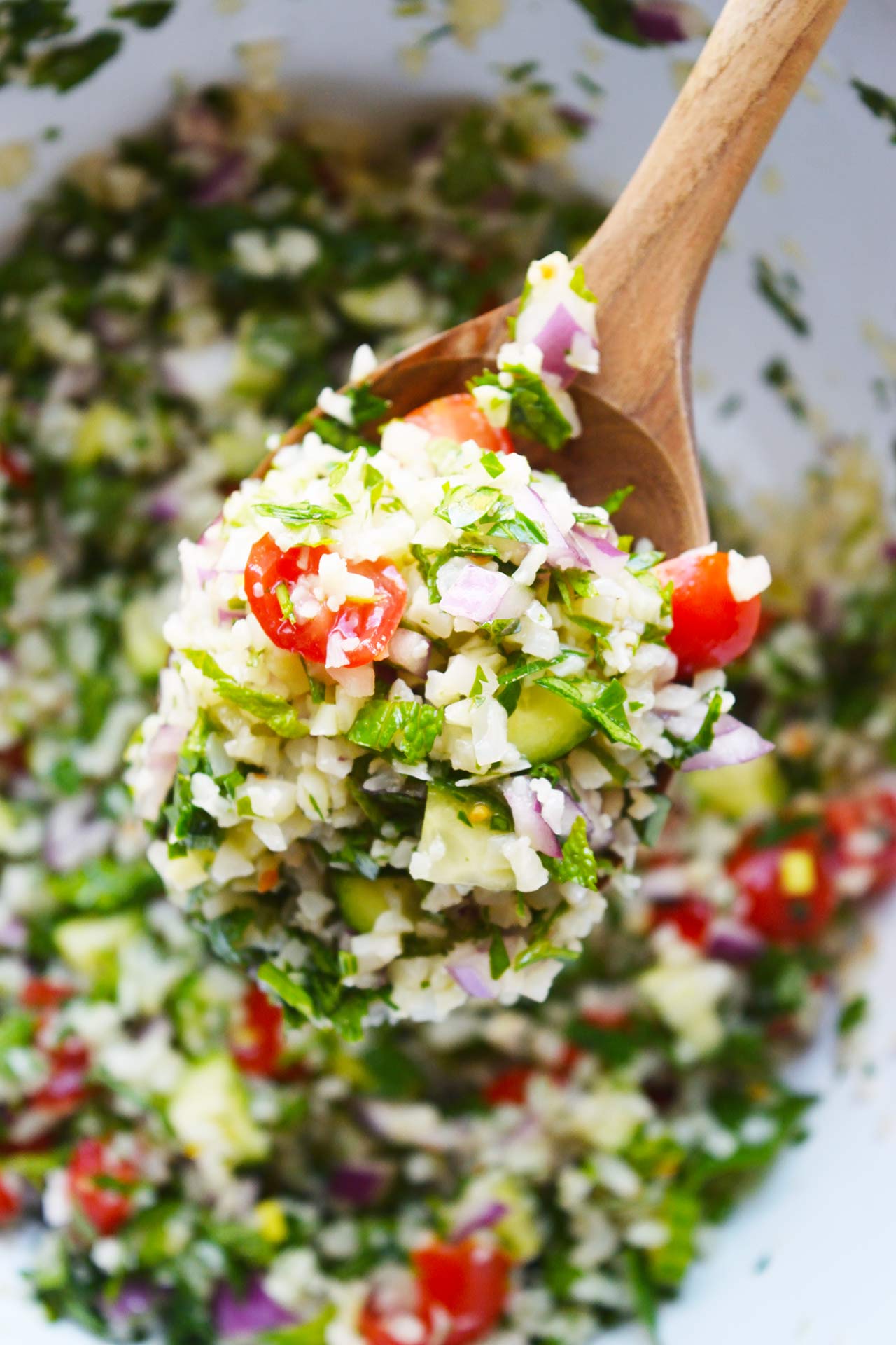 An overhead view of a wooden spoon full of Cauliflower Tabbouleh.