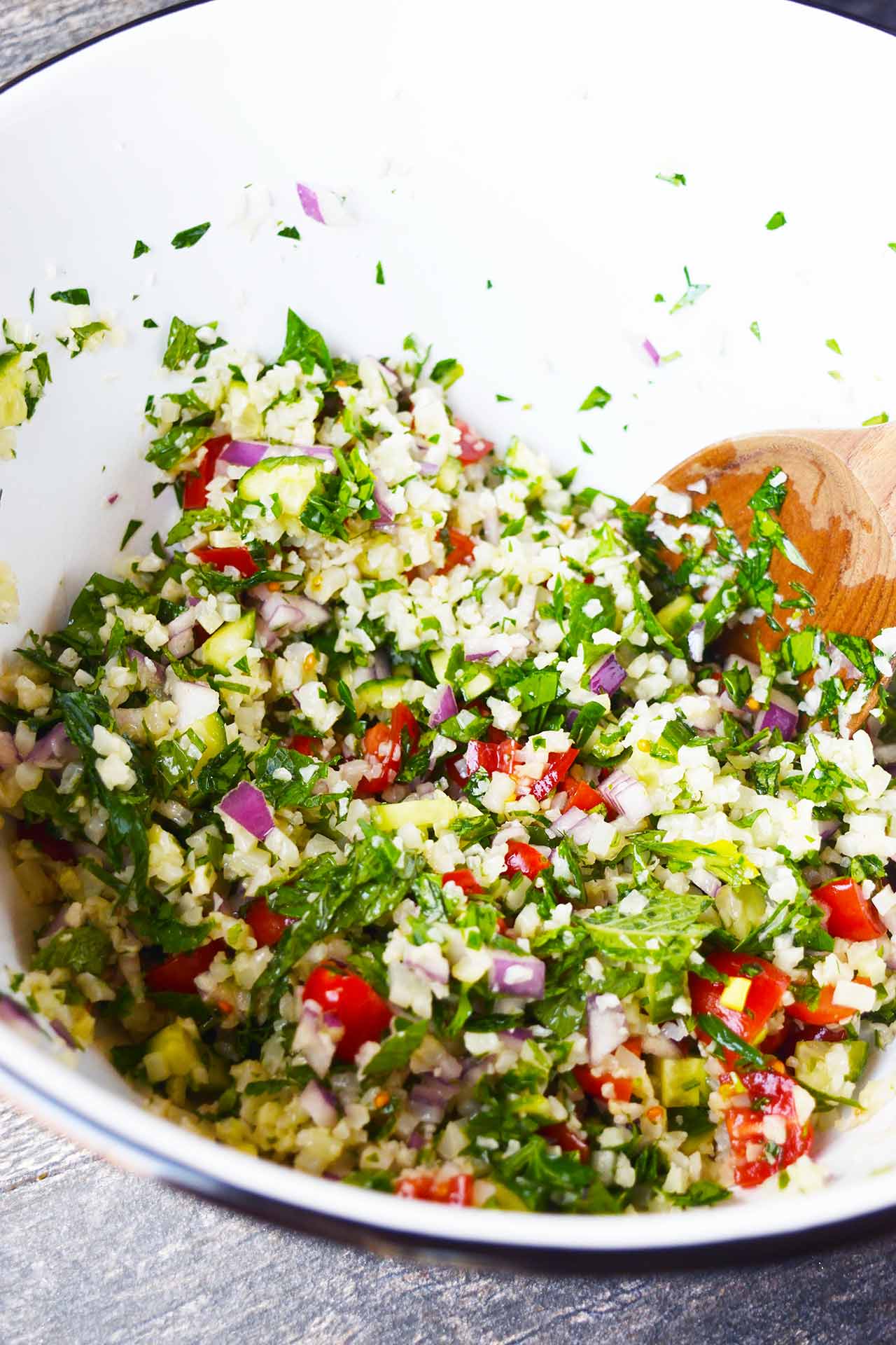 A side view of a white bowl with Cauliflower Tabouleh.