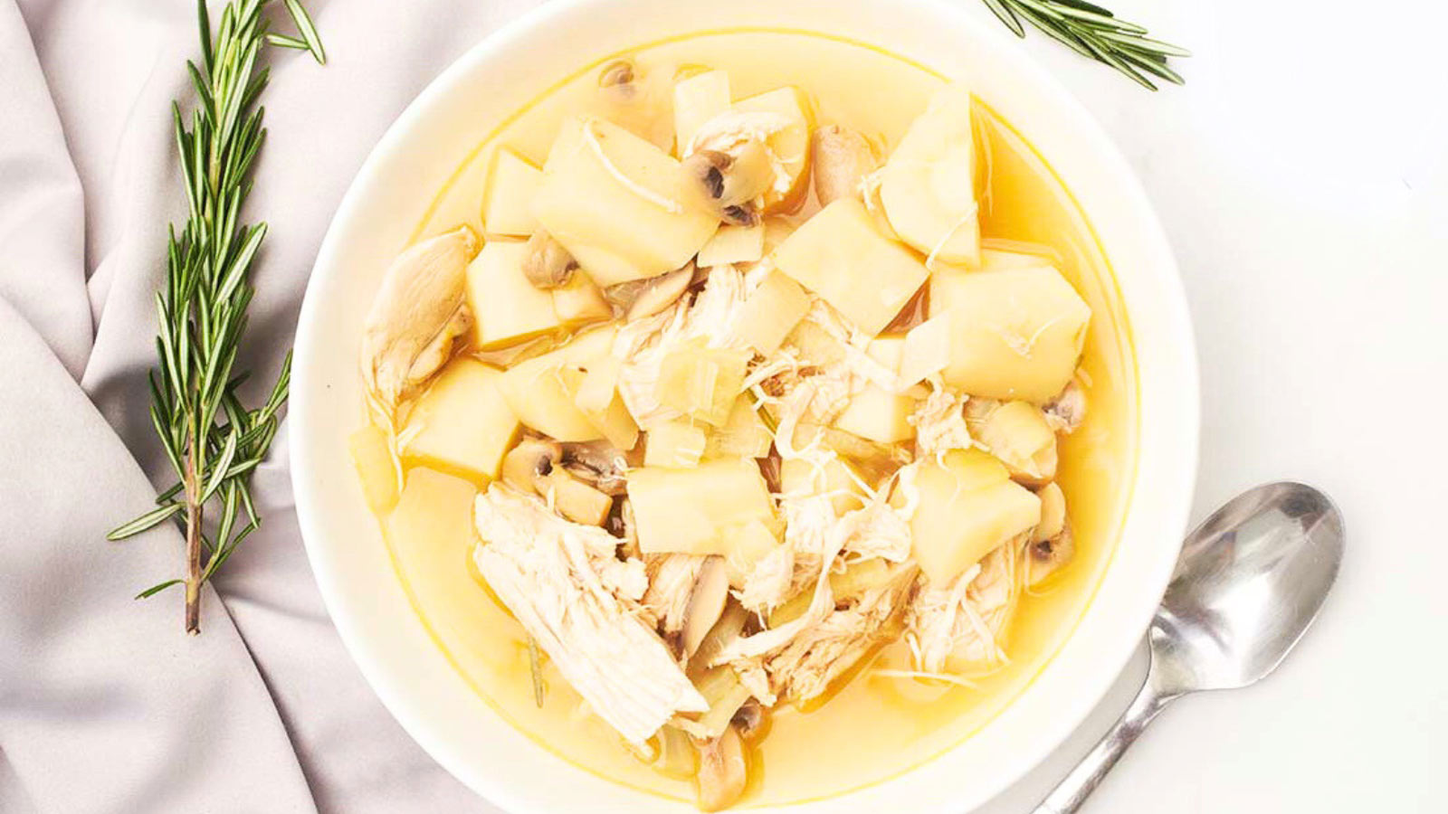 An overhead view of a white bowl filled with Chicken And Parsnip Soup.