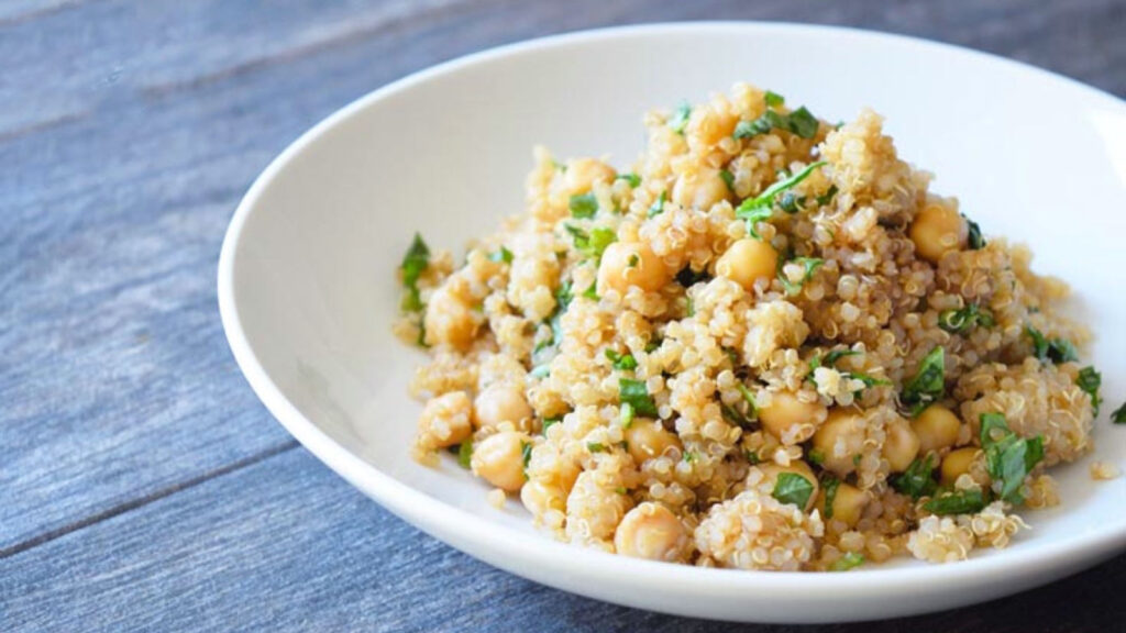 A side view of a white bowl filled with chickpea quinoa salad.