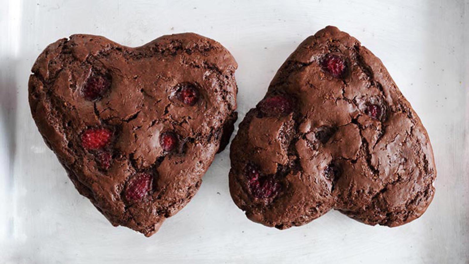 Two just-baked Healthy Chocolate Raspberry Cakes sitting on a sheet pan.