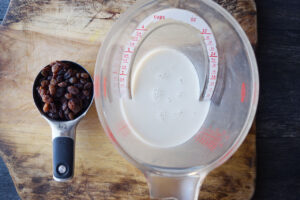 Condensed Milk Recipe ingredients in measuring cups on a wood cutting board.