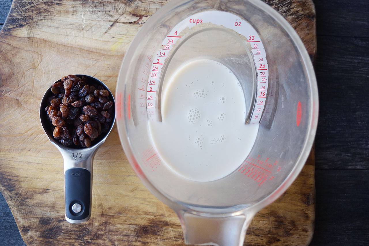 Condensed Milk Recipe ingredients in measuring cups on a wood cutting board.