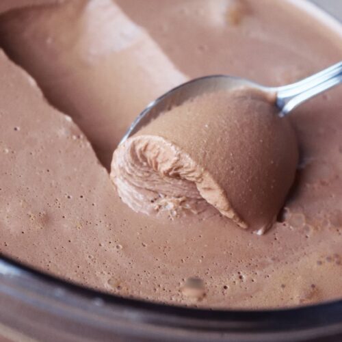 A closeup of a spoon scooping up some chocolate mousse.