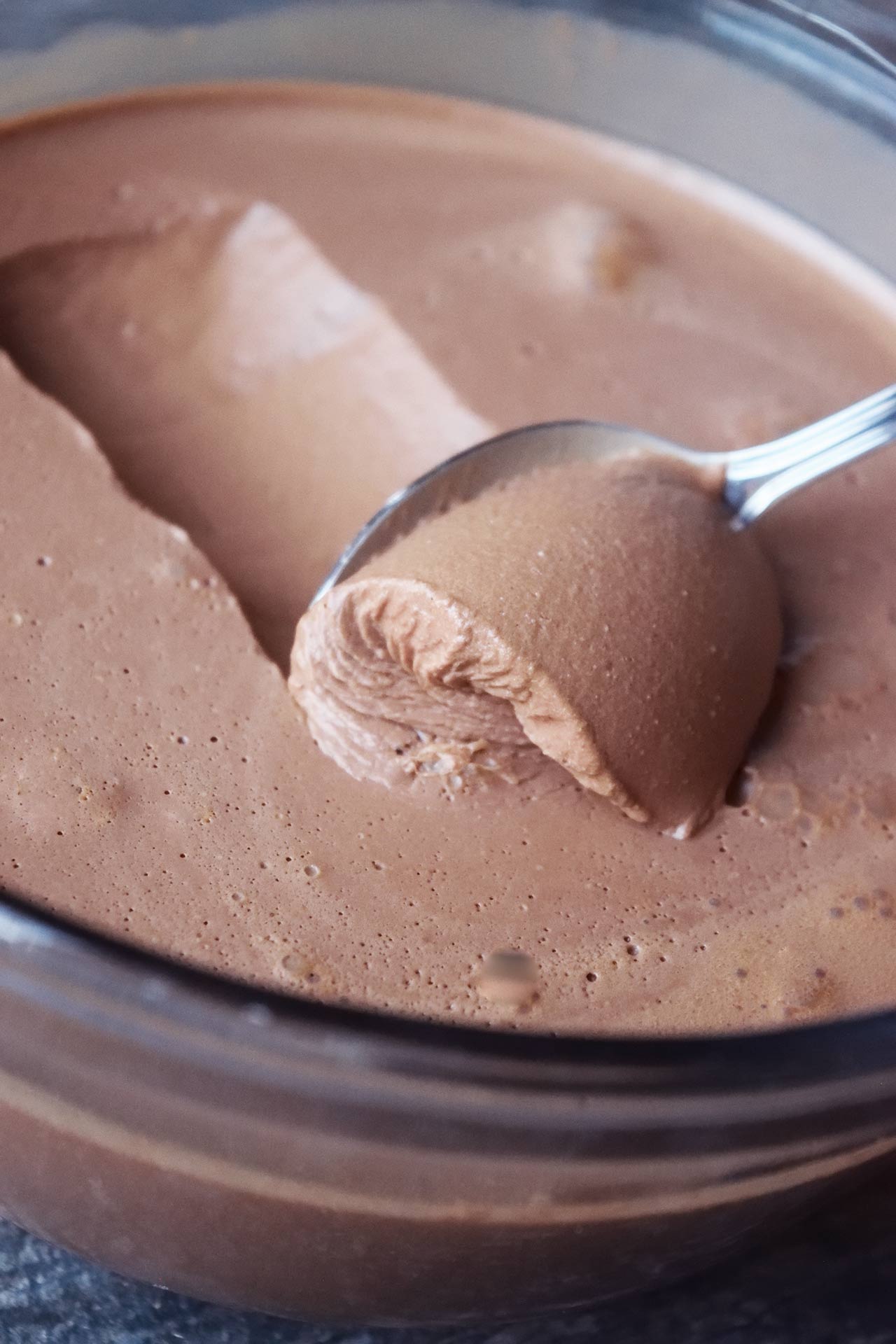 A closeup of a spoon scooping up some chocolate mousse.