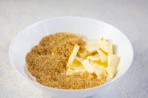 A white mixing bowl holds flour, sweetener and cubes of butter.