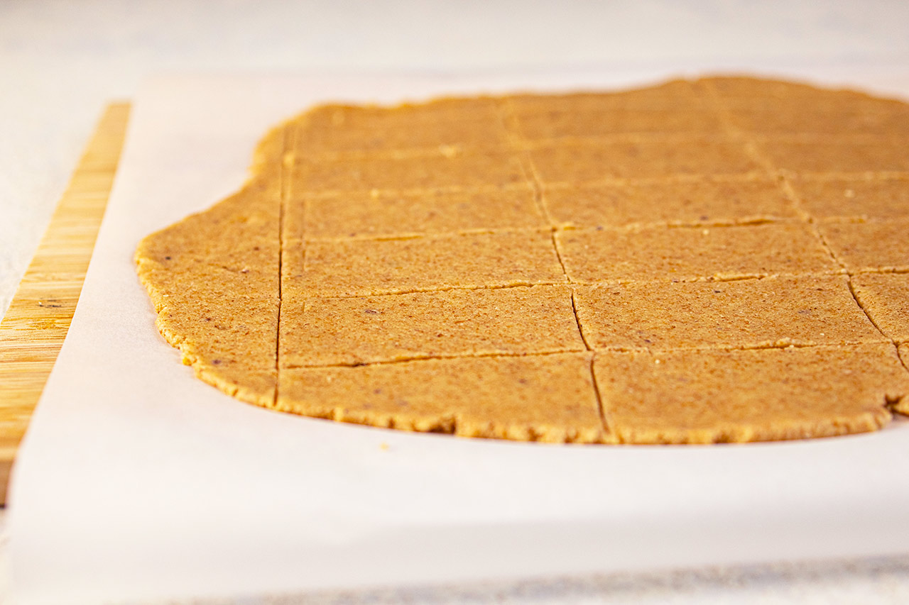 Graham Cracker dough rolled flat on parchment paper and cut into rectangles.