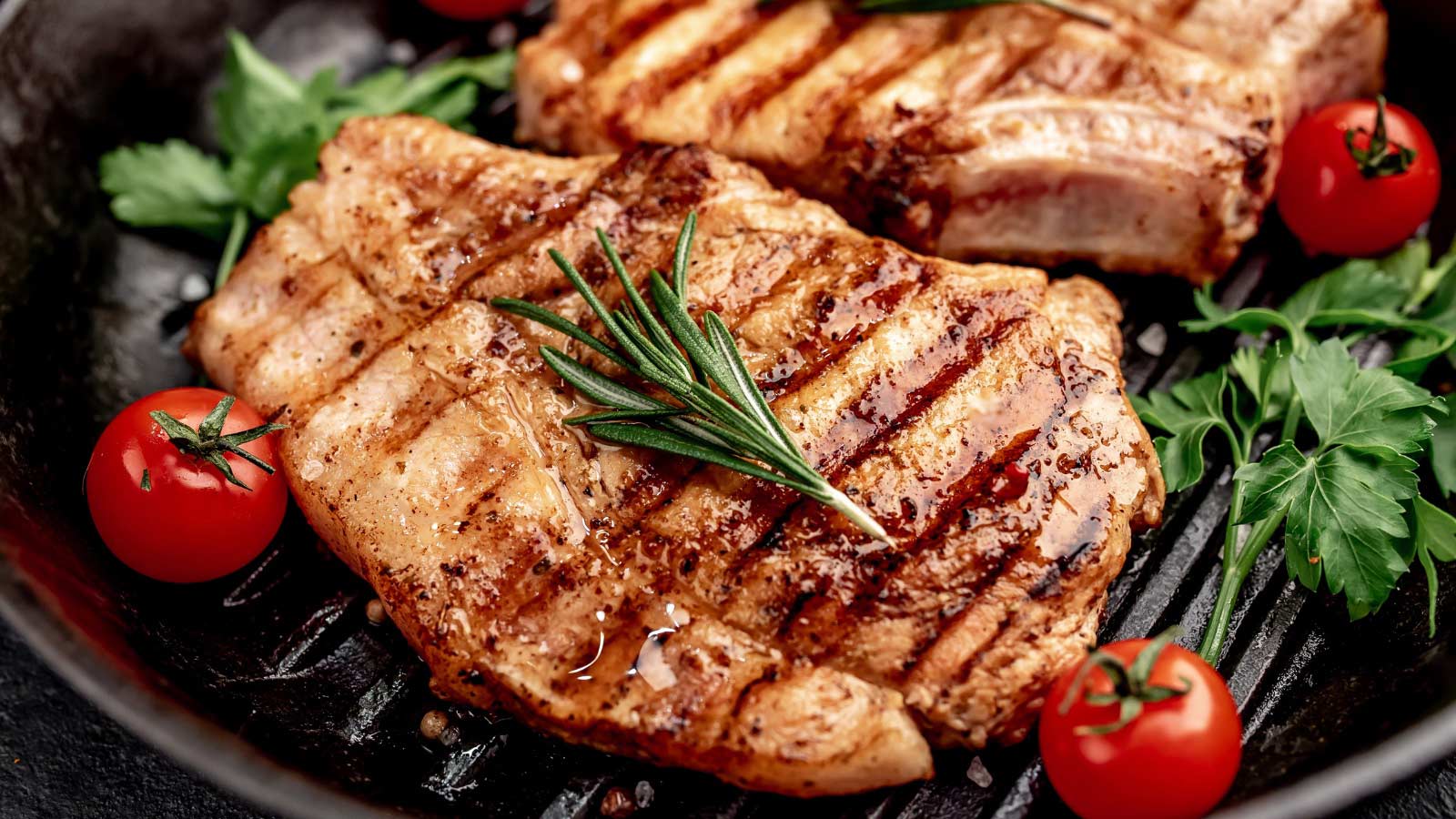 Grilled pork steaks in a grill pan with spices.