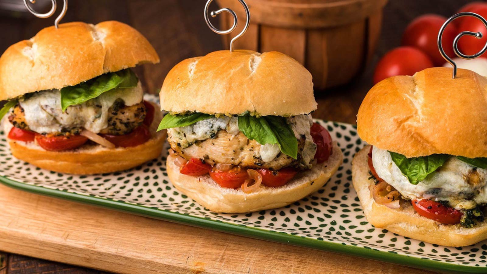 Three Italian chicken pesto sandwiches lined up on a platter.