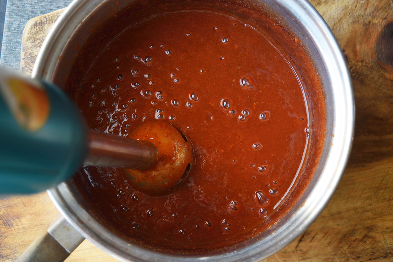 Blending the ketchup mix in a pot with an immersion blender.