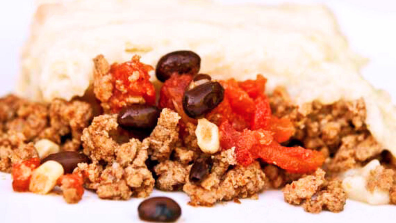 A closeup of a slice of Mexican Shepherds Pie on a white background.