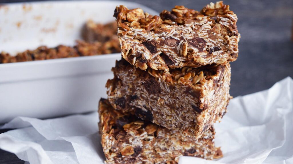 A stack of three No Bake Granola Bars sitting on a white piece of parchment paper.