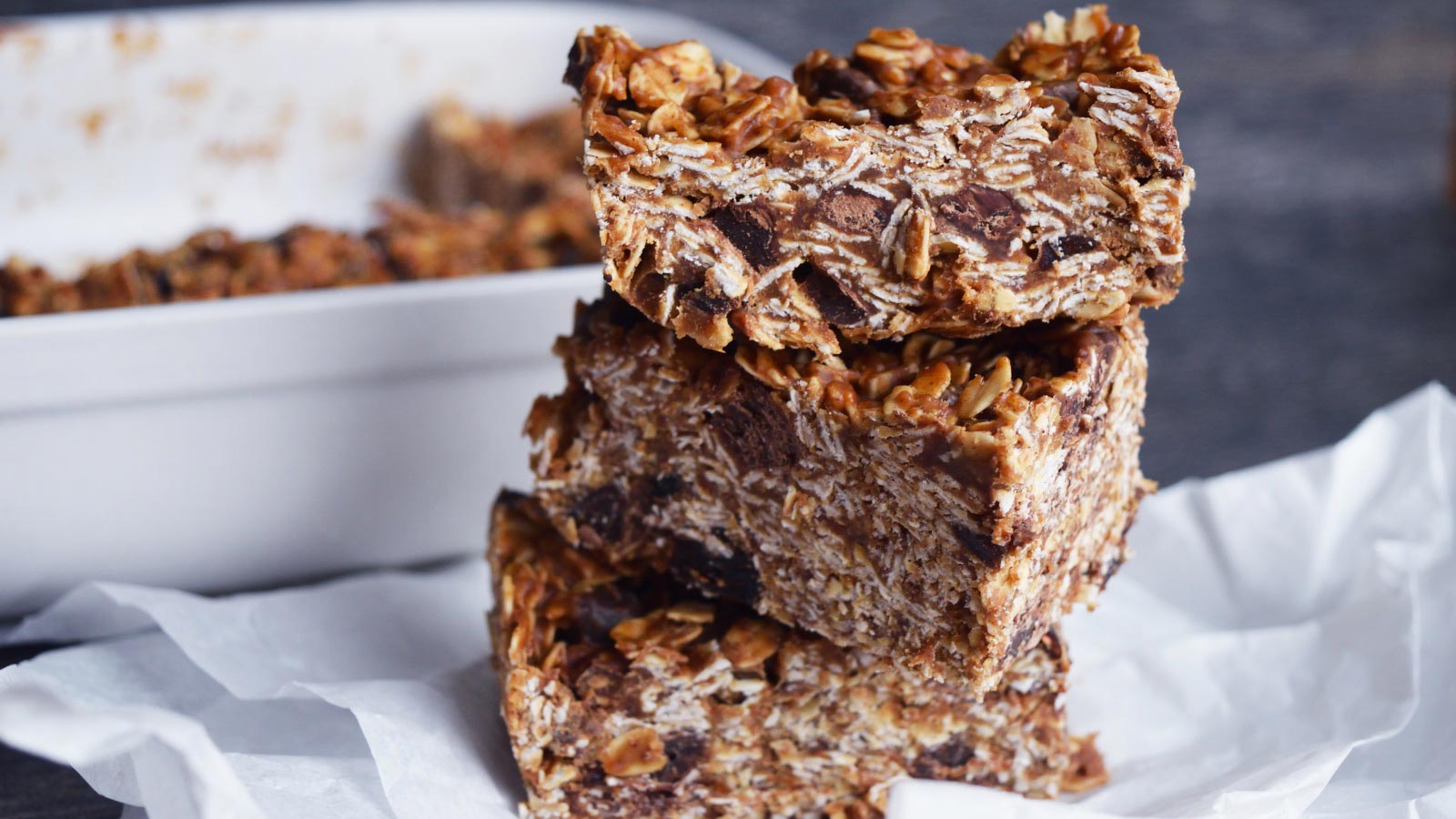 A stack of three No Bake Granola Bars sitting on a white piece of parchment paper.