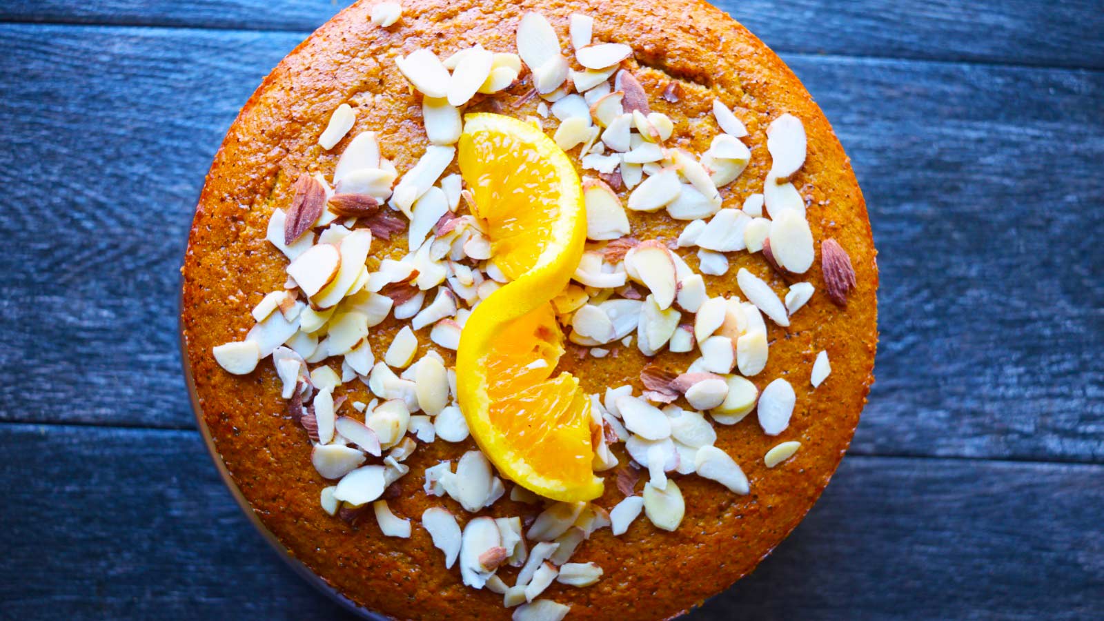Sliced almonds and an orange twist added as garnish to the top of the cake.